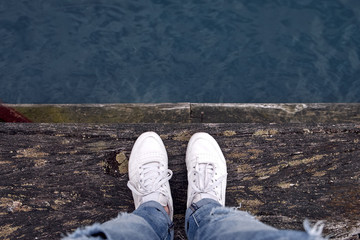 Person standing on wooden pier, top view above water