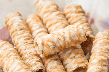 Crispy rolled wafer sticks, traditional dessert in Thailand, are collocated on the wood board.