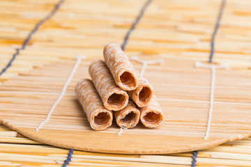 Crispy rolled wafer sticks, traditional dessert in Thailand, are collocated on the wood board.