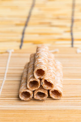 Crispy rolled wafer sticks, traditional dessert in Thailand, are collocated on the wood board.