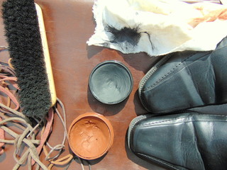 black shiny shoes with shoe polish, shoelaces, a cloth and a brush 