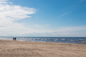 Jurmala, Latvia - April 16, 2017: The silhouettes of people enjoying romantic walking on sandy beach of the Baltic Sea
