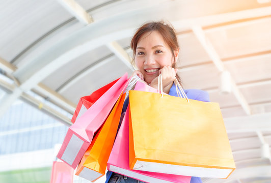 Cheerful shopping woman holding colorful bags.