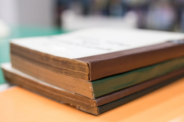 A stack of old books on table with blur book in library, education background