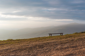 A chair at the edge of the mountain under the beam of morning light.