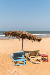 Beach chairs, small table, and an umbrella on a sandy beach in Goa, India
