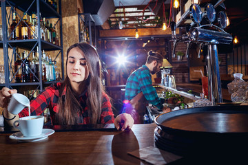 The barman barista's girl makes coffee on the bar.