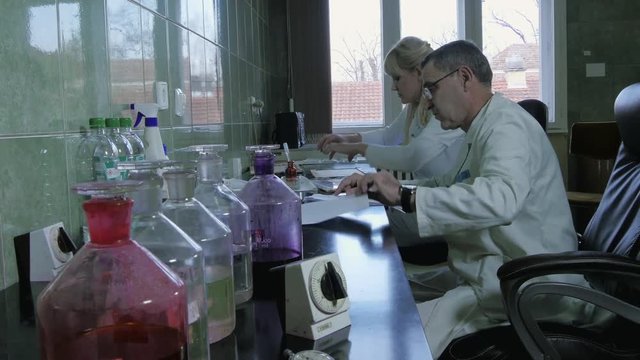 Female and male laboratory technicians during work process in pathological lab preparing and analyzing a tissue samples, concept pathologist analysis, crane shot, room interior, active realistic scene