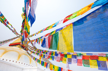Boudhanath stupa and its colorful flags in daylight.