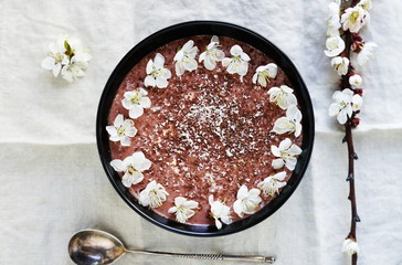 Breakfast banana chocolate smoothies in dark bowl  on a light linen background. Top view