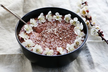 Breakfast banana chocolate smoothies in dark bowl  on a light linen background