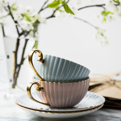 Letters in craft envelopes with a bow on a marble table next to tea cups and a vase with spring flowering branches