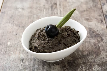  Black olive tapenade with anchovies, garlic and olive oil on wooden background     © chandlervid85