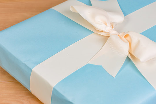 Blue wrapped gift with cream colored bow with copy space and a very shallow depth of field