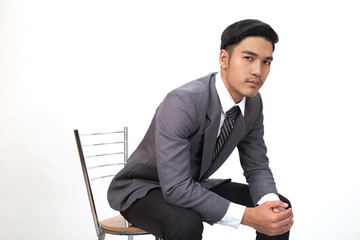 Businessman wearing gray suit sitting on chair and posing over white Background