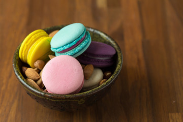 Tasty macaroons and cup of milk with almond on wooden background