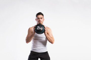 Handsome fitness man holding medicine ball, studio shot.