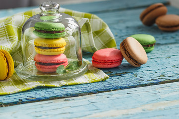 Green, pink and yellow french macarons under the glass on the wooden boards
