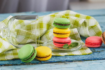 Green, pink and yellow french macarons under the glass on the wooden boards