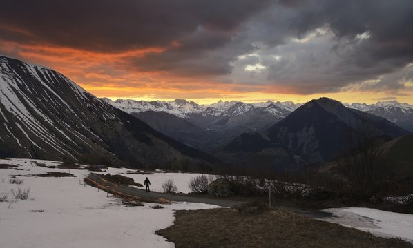 A lone hiker pauses to watch a majestic sunset in the Alps, Arvan valley, Savoy, France