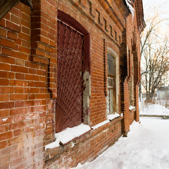 Fragment of an old one-story building in the Russian province. House of bricks with bars on the windows.