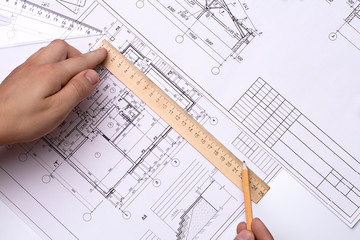Man architect draws a plan, schedule, design, geometric shapes with a pencil and a wooden ruler. The figure is close to the transparent line of triangle