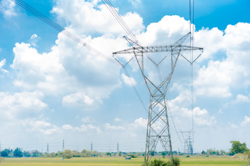 Electricity pylon silhouetted against blue sky wih cloud background. High voltage tower 