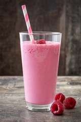 Raspberry smoothie in glass on wooden table
