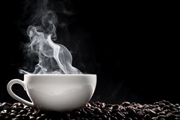 Steaming coffee cup put on coffee beans isolated on black background.