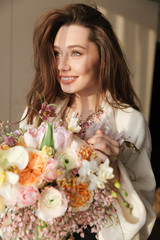 Happy woman standing and holding bouquet of flowers at home