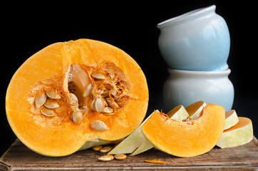 Half pumpkin and pots for cooking on a black background