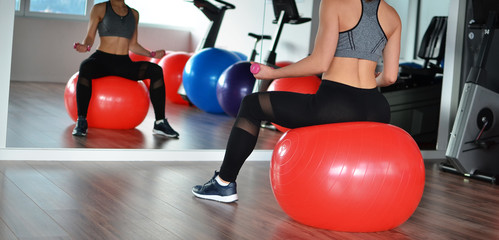 Woman sitting on pilates ball in gym