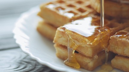 Honey pouring on a fresh waffles. Breakfast with Belgian waffles
