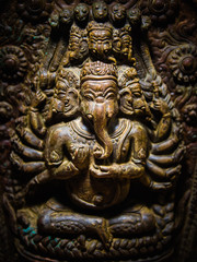 Fototapeta na wymiar Intricately carved statue of the Hindu God Ganesha (elephant head) on display in the museum at Patan's Durbar Square, Nepal. Vignette and dramatic lighting.