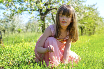 Fototapeta premium The little girl in a blossoming orchard