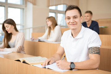 Obraz premium Handsome young man studying in university with his classmates