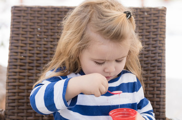 Cute baby boy eating tasty ice cream in outdoor cafe