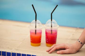 Enjoying your vacation. Closeup female hands on a background of cocktail and pool.