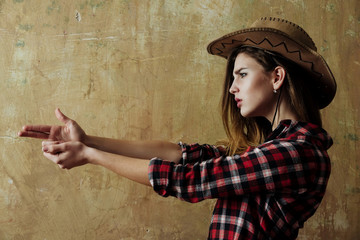 Pretty girl in stylish cowboy hat showing finger gun