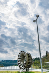 Wasserkraftturbine und Lichtmast vor Wolkenhimmel