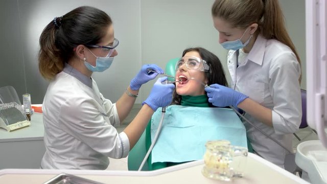 Work of two dentists. Patient in dental safety glasses.