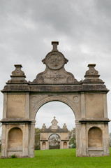 Fototapeta na wymiar Stone monument with two arches in a formal English garden