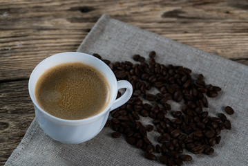 Coffee cup and beans on a wooden table.
