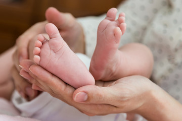 Obraz na płótnie Canvas Parent hands gently holding baby feet from below
