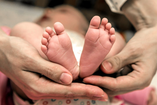 Parent hands gently holding baby feet from below