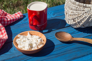 Basket, a cup of milk and cottage cheese on a table of blue boards