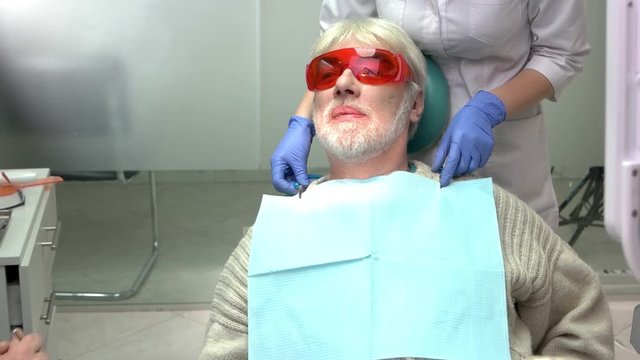 Dentist with elderly patient. Dental bib and safety glasses.