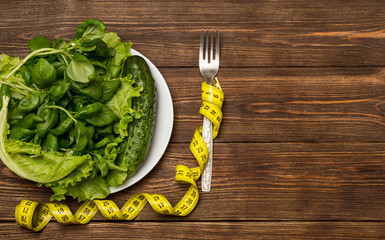 Healthy eating, dieting, slimming and weigh loss concept.  Greens a nd vegetables on wooden background with space for text. Vegetarian food