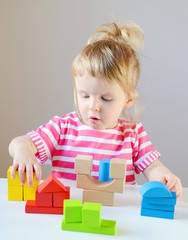 Little baby girl playing with wooden colorful cubes