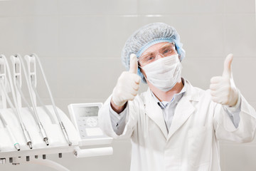 Portrait of happy male dentist wearing lab coat while sitting in clinic